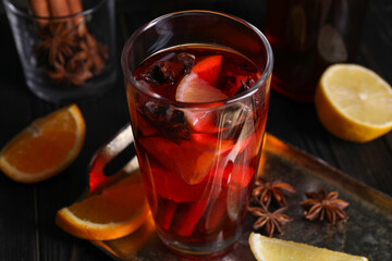 Glass of aromatic punch drink and ingredients on table, closeup