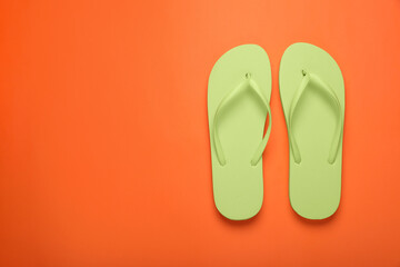Stylish light green flip flops on orange background, top view. Space for text