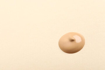 Drop of skin foundation on beige background. Space for text