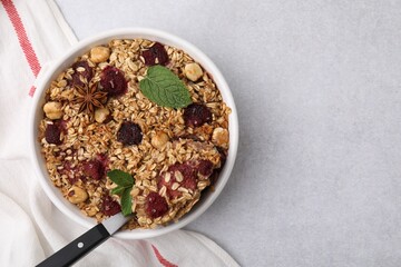 Tasty baked oatmeal with berries, nuts and anise star on light grey table, top view. Space for text