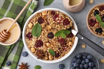 Tasty baked oatmeal with berries and nuts served on light grey table, flat lay