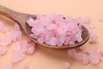 Spoon with pink sea salt on beige background, closeup