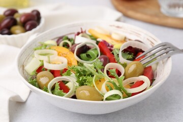 Bowl of tasty salad with leek and olives on light table, closeup