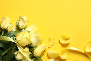 Obraz premium Beautiful roses, petals and ribbon on yellow background, flat lay. Space for text
