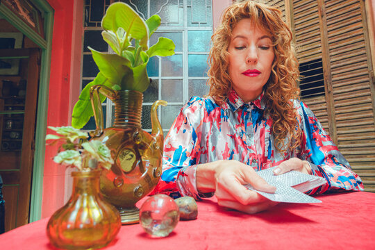 adult tarot reader woman starting reading by removing card from deck to place it on table