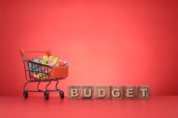 Text on BUDGET on the wooden cubes. A shopping cart filled with colorful cubes at the side. Budget...