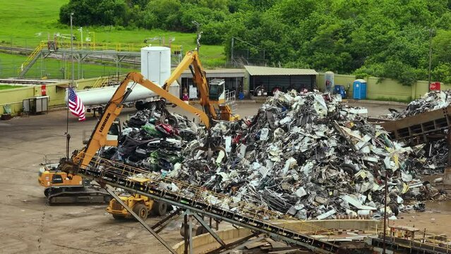 Old vehicle utilization junkyard with claw crane manipulator machines lifting and disposing cars for scrap metal. Transport equipment at crashed auto disposal site