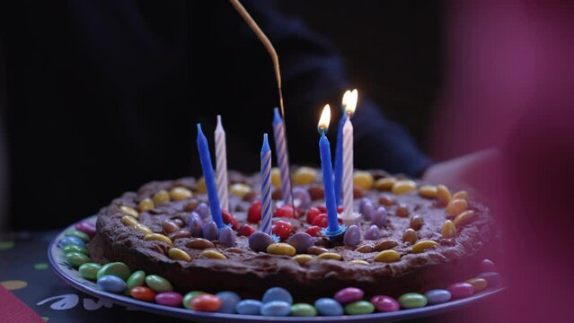 Close-up of a hand lighting birthday candles, chocolate cake of child celebration