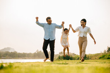 Happy family running through a beautiful green field on a sunny summer day, enjoying the freedom...