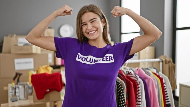 Radiant, strong-armed young hispanic woman volunteer exuding confidence, smiling beautifully in charity center