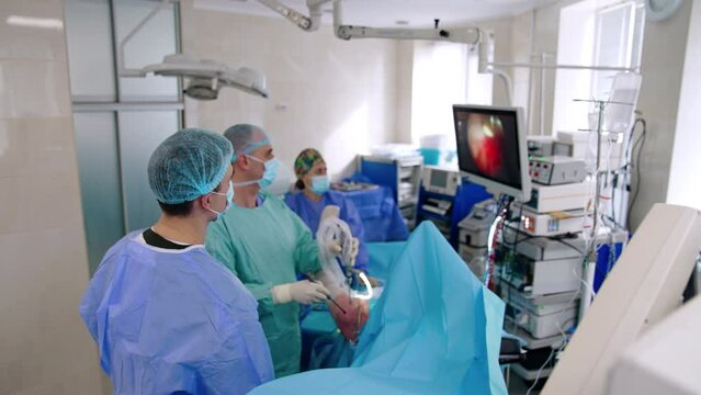 Minimal invasive surgery on the leg. Two doctors co-work at operation. Surgeons intently look at the monitor.
