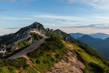 朝日を浴びる岩が光る燕岳と自然の山々と緑