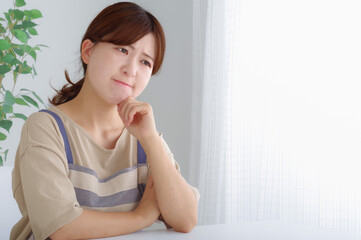 Fototapeta premium 頬杖をついて考え事をするエプロン姿の女性