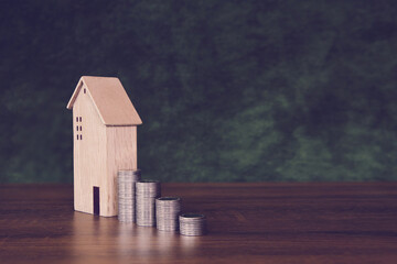 Coins stack in graph shape with wooden house for real estate or money savings planning and bank home loan or financial investment insurance.