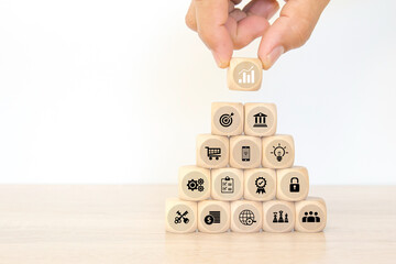 Hand choose cube wooden block stack pyramid with graph and business strategy icon for target goal to growth and financial marketing analysis or human resource management and investment concepts.