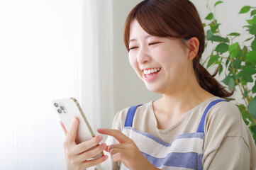 笑顔でスマホを持つエプロン姿の女性