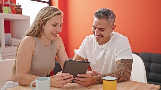 Man and woman couple using touchpad sitting on table at dinning room