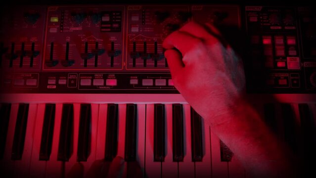 Synthesizer Musical Instrument Close Up, with Hand Tweaking, Adjusting  Buttons and Knobs. A moody lit modern, analogue synthesizer with the user adjusting the parameters of the sound.