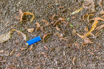Blue disposable cigarette lighter laying on ground.