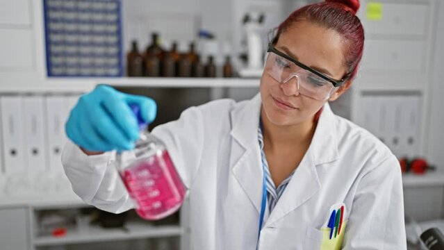 Hardworking young redhead scientist masterfully measuring liquid in a bottle at her high-tech laboratory, ensuring utmost safety and precision