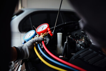 Hand of car mechanic technician use meter to check car air conditioner system heat problem and fix...