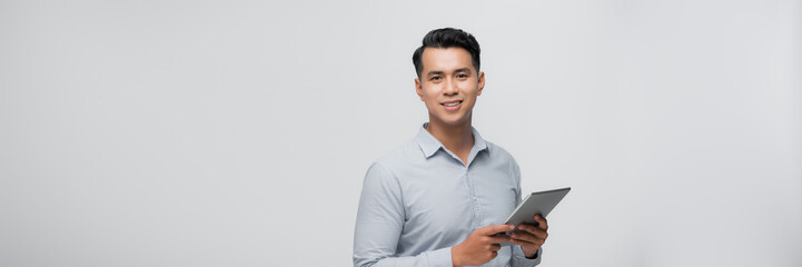 A portrait of a young asian man holding a digital touch screen tablet computer on white background.