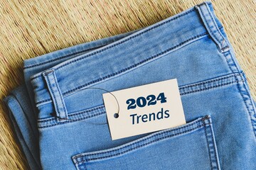 Close-up of blue jeans with tag message 2024 trends. Fashion trends concept. top view, korai grass...