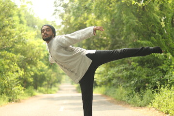 An Indian Boy wearing Khadi Kurta and a Bandana or neck gaiter standing on the road with green...