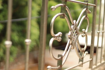 A Chrome silver coloured horizontal railing with abstract pattern in between with bokeh background 