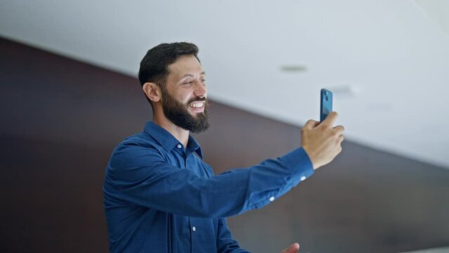 Young hispanic man business worker make selfie by smartphone at the office
