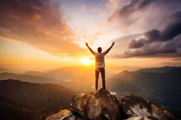 Foto op Aluminium A man stands on top of a mountain and looks into the distance at sunset, concept image of success © evening_tao
