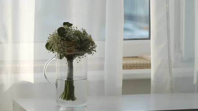 withered white wedding bouquet in a vase by the window