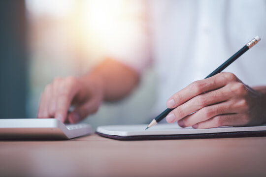 Businessman using a calculator to calculate numbers ,profit and loss statement review of company performance ,cost analysis ,financial paperwork ,Calculation of tax information reports