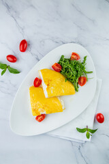 French tall omelette with arugula and cherry tomatoes top view