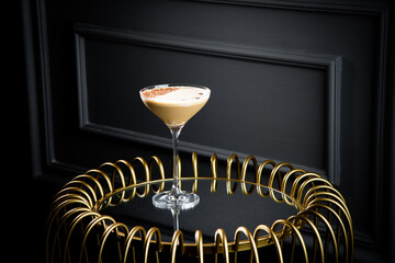 iced latte with foam in a martini glass on a dark background