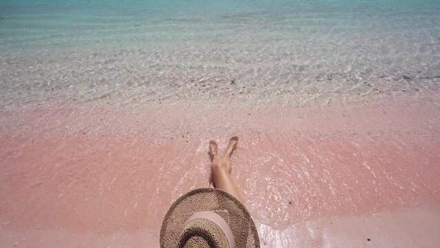 Young female tourism enjoying the tropical pink sandy beach with clear turquoise water at Komodo islands in Indonesia