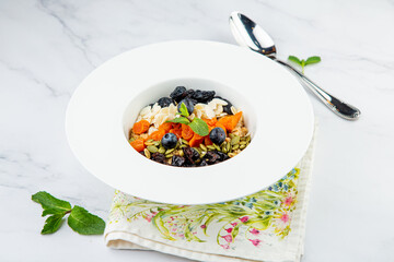 deep plate with cereals, berries, pistachios, dried apricots and raisins side view