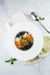 deep plate with cereals, berries, pistachios, dried apricots and raisins top view