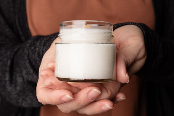 white coconut wax candle in female hands, cozy atmosphere