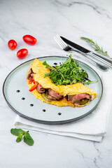 Breakfast of eggs with meat, herbs and drops of sauce in a round plate side view