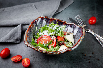 salad with tomatoes, feta cheese, lettuce and parsley in an unusual bowl side view
