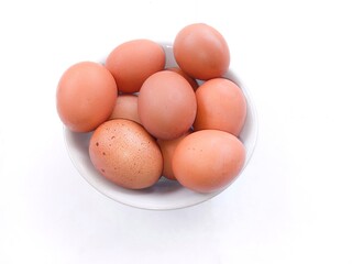 a pile of chicken eggs in a white bowl isolated on a white background. eggs with brown shells. healthy food
