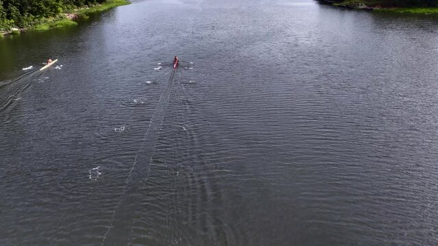Drone footage of three athletes participating in a sculling race on a sunny day