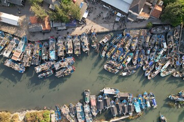 Aerial view of anchored fishing boats at the river harbor by the sea. Pantai Widuri Pemalang,...