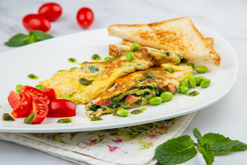 Breakfast of eggs and vegetables with cherry tomatoes and slices of bread in a white plate side view