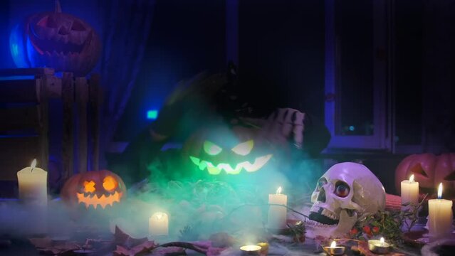 Festive carved pumpkin dancing with creepy skeleton hands invite friends guests to join Halloween festival party by pointing finger for you, spooky traditional decoration day of dead, fast shot.