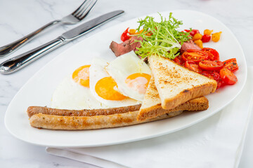 Fototapeta na wymiar scrambled eggs with vegetables, cherry tomatoes, bread, herbs and sausages on a white plate side view