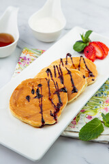 pancakes with chocolate syrup with strawberries and mint
