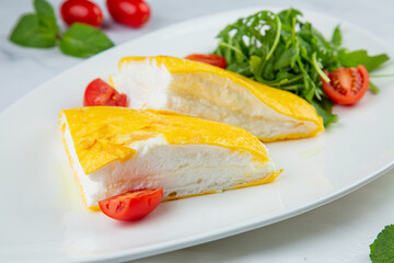 French tall omelette with arugula and cherry tomatoes side view