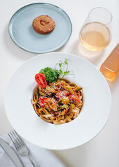 udon noodles with sesame seeds and herbs in a white plate top view